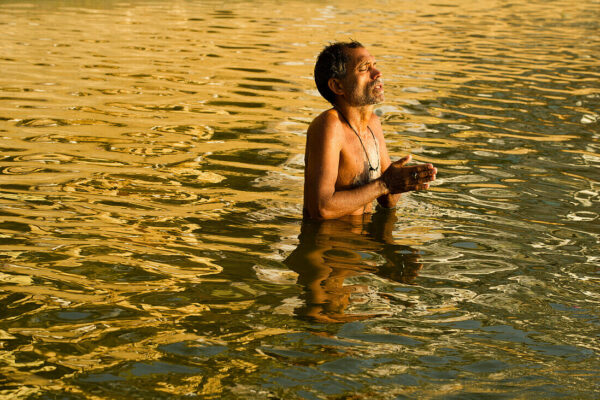 70479296-Devotee-with-hands-folded-praying-in-the-yellowish-waters-of-the-Ganges-river-on-sunrise-in-Varanasi-India